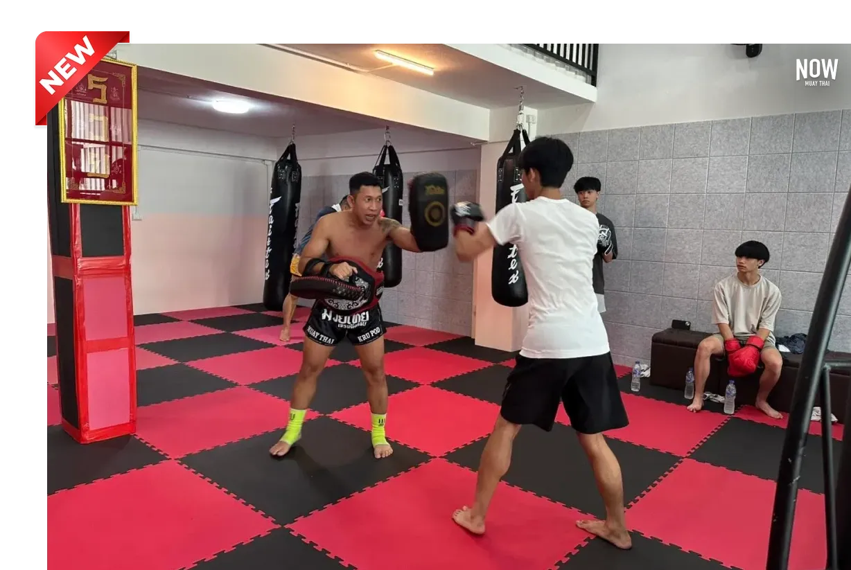 Trainer holding Thai pads while a student practices striking during a Muay Thai class at Kru Frame Muay Thai Training Club in Chiang Mai
